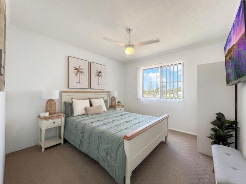 a white bedroom with a bed and a window at Seabreeze 7 in Tuncurry