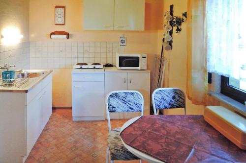 cocina con mesa, sillas y microondas en Cottage, Jagdhof, en Judenbach