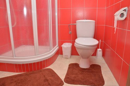 y baño con ducha, aseo y azulejos rojos. en Hotel Růženy, en Hustopeče