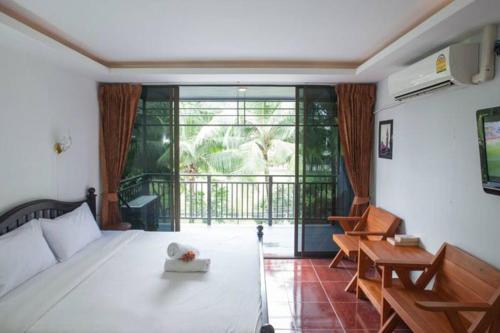 1 dormitorio con cama blanca y balcón en Kamala bay inn, en Kamala Beach