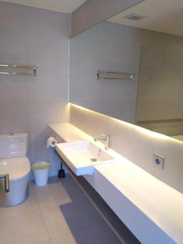 a bathroom with a sink and a mirror and a toilet at Ariama Serviced Residence in Jakarta