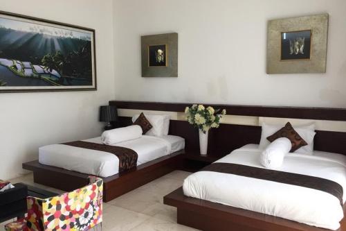 a hotel room with two beds and a vase of flowers at Aldeoz Villa Nusa Dua in Nusa Dua