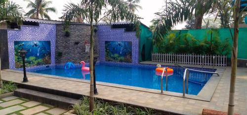 a large swimming pool with an aquarium in a house at Coastal Bay Inn By Gemstone Hospitality in Alibaug