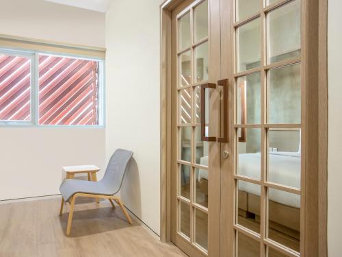 a room with a chair and a glass door at Swiss-Belexpress Cilegon in Cilegon
