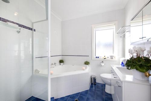 a white bathroom with a tub and a toilet and a sink at Charm on Carrington in Adelaide