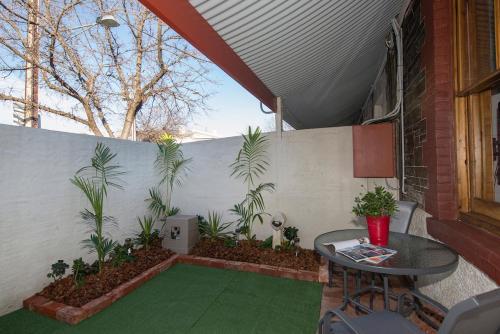 a patio with a table and a wall with plants at Charm on Carrington in Adelaide