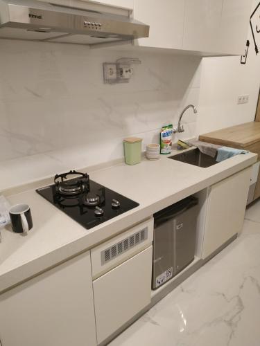 a white kitchen with a stove and a sink at Apartemen Scandinavian 20m dengan 1 Kamar Tidur dan 1 Kamar Mandi di BSD Sky House BSD in Cilenggang