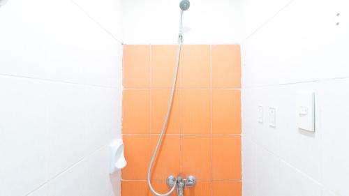 a shower in a bathroom with orange and white tiles at RedDoorz Hostel @ Molino Beach Resort in Zambales