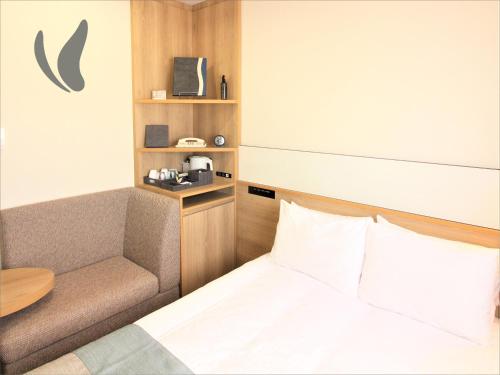 a bedroom with a bed and a chair and a table at Almont Hotel Naha Omoromachi in Naha