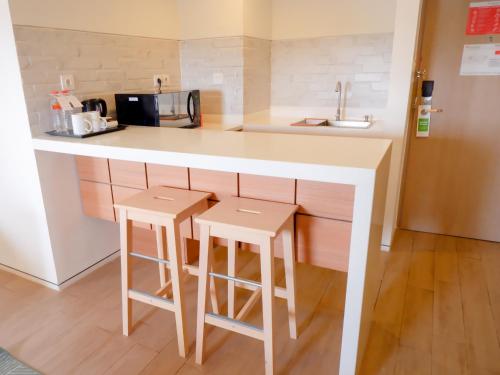 a kitchen with a counter and two stools at Swiss-Belexpress Cilegon in Cilegon
