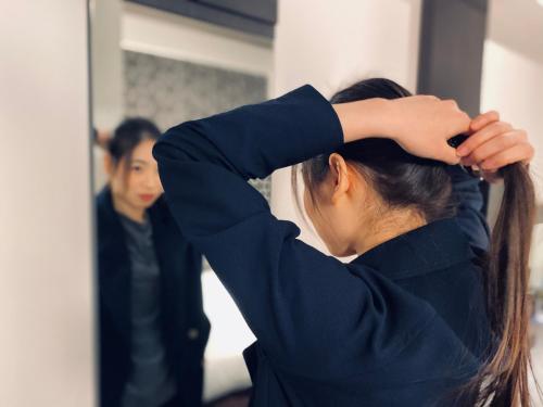 a woman brushing her hair in front of a mirror at Hotel Halrotto Fukuoka Hakata in Fukuoka