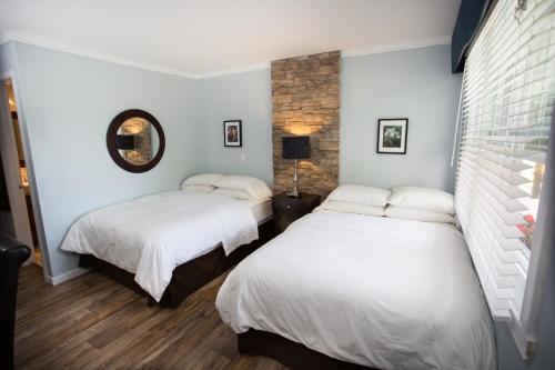 Habitación con 2 camas, paredes blancas y suelo de madera. en Studiotel Bromont, en Bromont