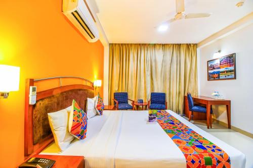 um quarto de hotel com uma cama grande e cadeiras em FabHotel F9 NFC em Nova Deli