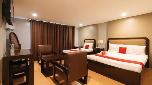 a hotel room with two beds and a table and a desk at RedDoorz Plus Park-Lay Suites Kidapawan City in Kidapawan