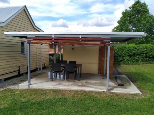 a patio with a table and chairs under a roof at The Radford Couples Cottage Heart of Stanthorpe in Stanthorpe