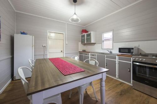 a kitchen with a table and chairs and a refrigerator at The Radford Couples Cottage Heart of Stanthorpe in Stanthorpe