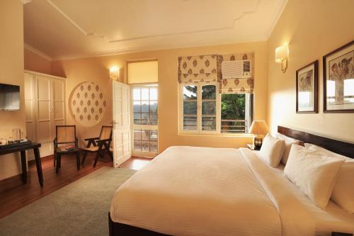 um quarto com uma cama, uma secretária e janelas em Lamrin Boutique Cottages, Rishikesh em Rishikesh