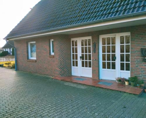 a brick house with white doors and a brick driveway at Ferienwohnung im schönen Holsteiner Auenland in Brande-Hörnerkirchen