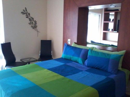 Genie's Nest 1 في بريتوريا: غرفة نوم بسرير ازرق واخضر مع كرسيين