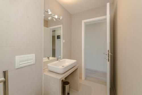 a white bathroom with a sink and a mirror at Apartment Amazing Island in Povljana