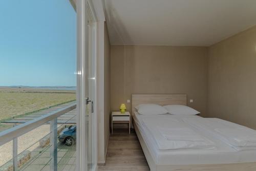 a bedroom with a bed and a balcony with a view at Apartment Amazing Island in Povljana