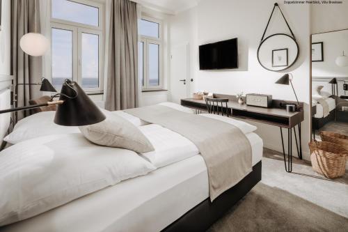 a bedroom with a large bed with a desk and a desk at Villa Breeksee in Norderney