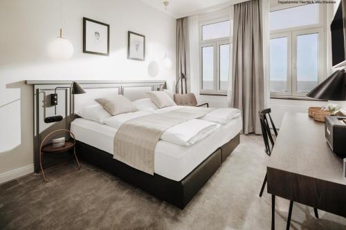 a hotel room with a large bed and a desk at Villa Breeksee in Norderney