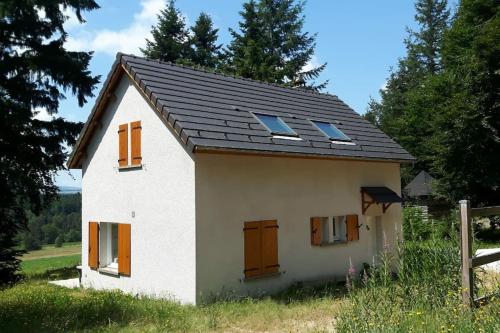 una pequeña casa blanca con techo negro y ventanas en PETITE MAISON AU CALME AVEC VUE MAGNIFIQUE !, en Le Chambon-sur-Lignon