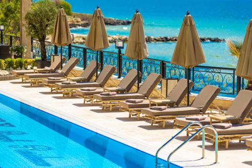 a row of lounge chairs and umbrellas next to a swimming pool at Onyx Beach Residence - Free Parking & Beach Access in Sveti Vlas
