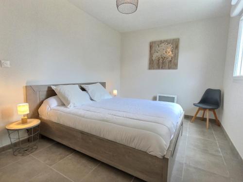 a bedroom with a large bed and a blue chair at Vacancéole - Résidence La Dune in Sérignan