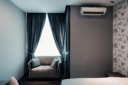 a bedroom with a bed and a chair and a window at Le'venue Hotel in Bangi