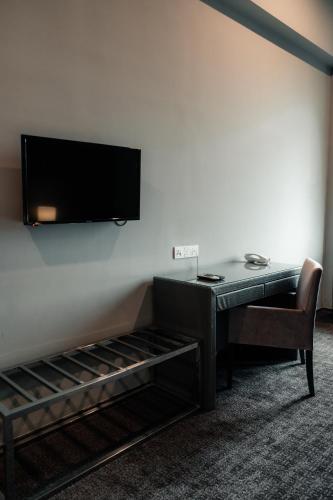 a room with a desk and a television on a wall at Le'venue Hotel in Bangi