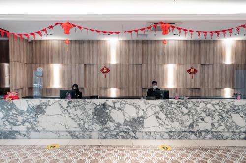 two people sitting at desks in a large room with red decorations at Le'venue Hotel in Bangi