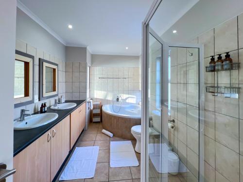 een badkamer met 2 wastafels, een toilet en een douche bij Waterfront Edge B5 in Swakopmund