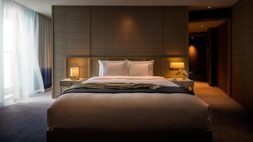 a bedroom with a large bed with two tables and two lamps at Signiel Busan in Busan