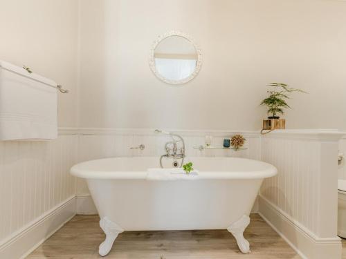 een badkamer met een wit bad en een spiegel bij Cottage Pie by Robberg in Plettenbergbaai