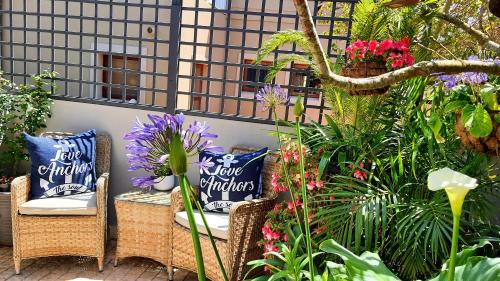 a patio with two chairs and flowers and plants at Amelia's by the Sea in Groot Brak Rivier