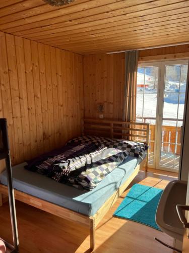 Cama en habitación de madera con ventana en Berghotel Furggstalden, en Saas-Almagell