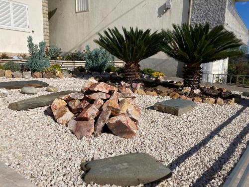 a garden with rocks and palm trees in front of a building at Monte das Cerejas in Montes da Senhora