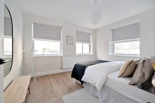 a white bedroom with a bed and a mirror at Exclusive Norman Road Apartment in St. Leonards