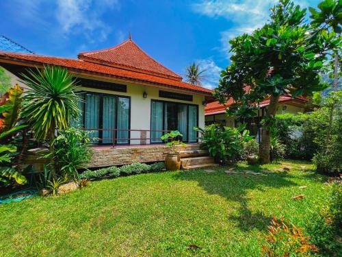 a house with a grass yard in front of it at Villas Chaba in Thong Nai Pan Yai