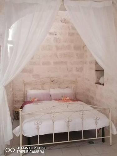 Schlafzimmer mit einem weißen Bett und weißen Vorhängen in der Unterkunft La casa di Gina in Ceglie Messapica