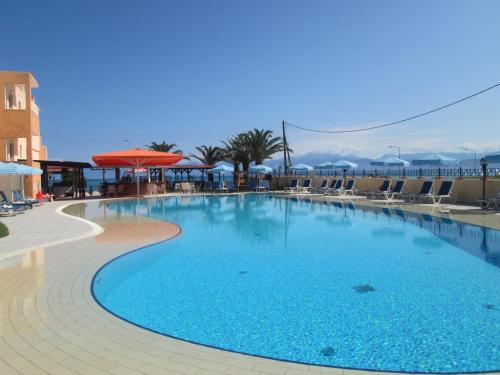 a large blue swimming pool with chairs and umbrellas at Ninos On The Beach Hotel in Roda