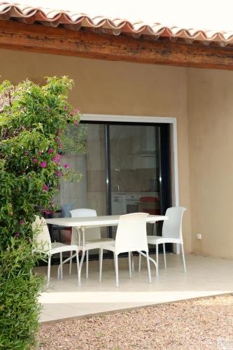 une table blanche et des chaises sur une terrasse dans l'établissement Casa Mia, à Porto-Vecchio