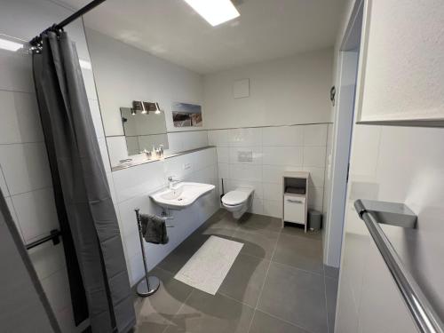 a white bathroom with a sink and a toilet at Apartment am Kirchplatz in Appenweier