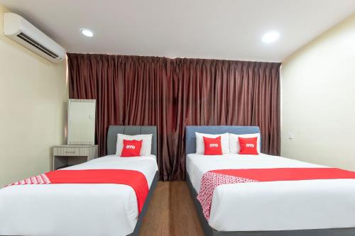 two beds in a room with red pillows at OYO 90380 Hotel Jasin in Jasin