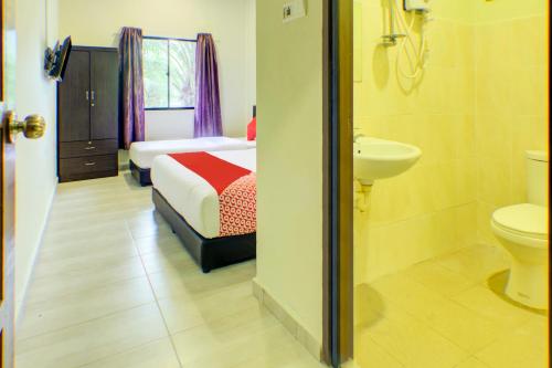 a bathroom with a bed and a toilet and a sink at Super OYO 89896 Sedili Inn Resort in Kota Tinggi