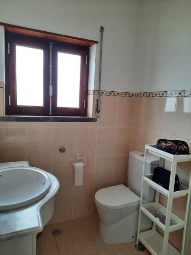 a bathroom with a sink and a toilet and a window at Casa d'Avo - Cascais-Estoril in São Domingos de Rana