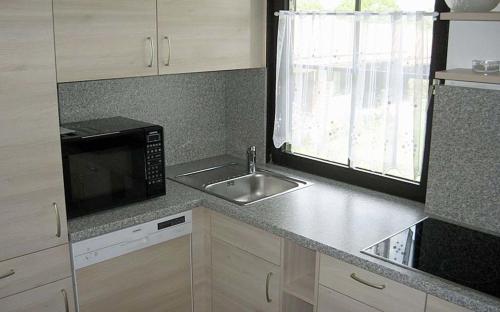 eine Küche mit einer Spüle und einer Mikrowelle in der Unterkunft Ferienhaus Nr 3, Typ A, Feriendorf Hochbergle, Allgäu in Bichel