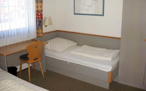 Cette petite chambre comprend un lit et une chaise. dans l'établissement Ferienhaus Nr 53, Kategorie Komfort, Feriendorf Hochbergle, Allgäu, à Karlsebene